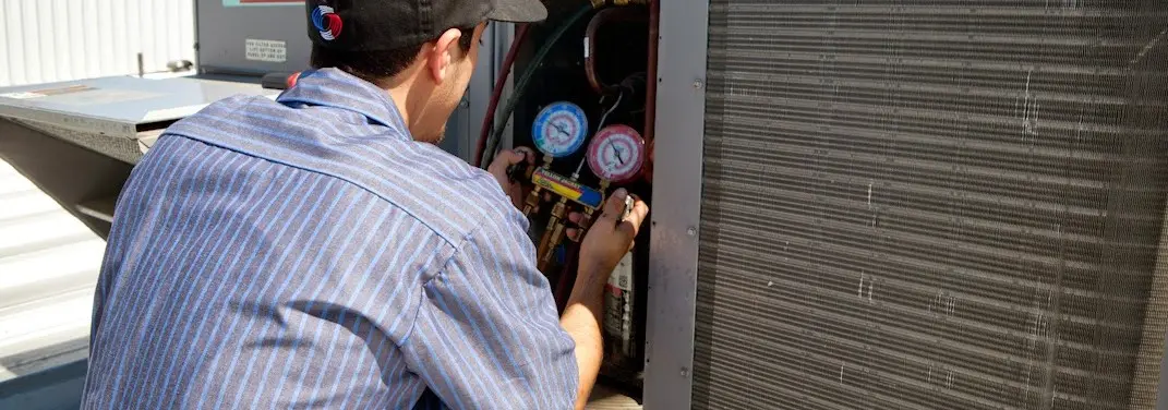HVAC technician servicing a condenser unit in Holmdel